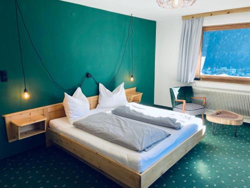 1 dormitorio con 1 cama con pared verde en Königin Serles - großzügig, gemütlich & nachhaltig en Fulpmes