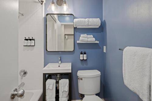 a bathroom with a toilet and a sink and a mirror at Sea Harbor Hotel - San Diego in San Diego