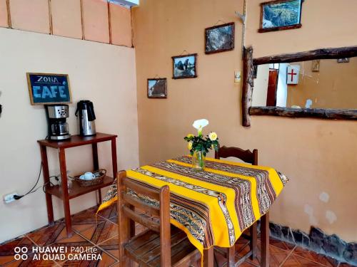 Una habitación con una mesa con un jarrón de flores. en hotel MISKY PUÑUY - Valle del Sondondo, en Andamarca