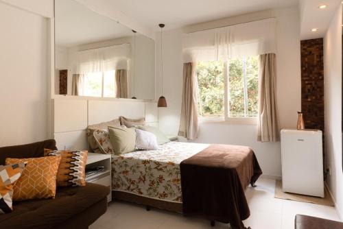 1 dormitorio con cama, sofá y ventana en Aparts -Hotel Cavalinho Branco, en Águas de Lindóia
