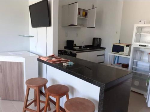 a kitchen with two stools and a black counter top at Summer Flat in Guarajuba