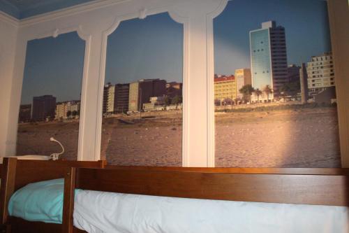 a bedroom with a view of a city from a window at Meeting Hostel in Figueira da Foz