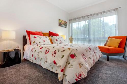 a bedroom with a bed and a orange chair at Wotama, Macedon B and B, Honour Ave, Mount Macedon in Mount Macedon