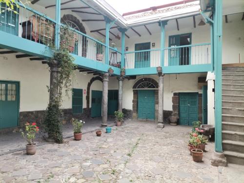 a courtyard of a building with green doors and potted plants at Hugos house in Cusco