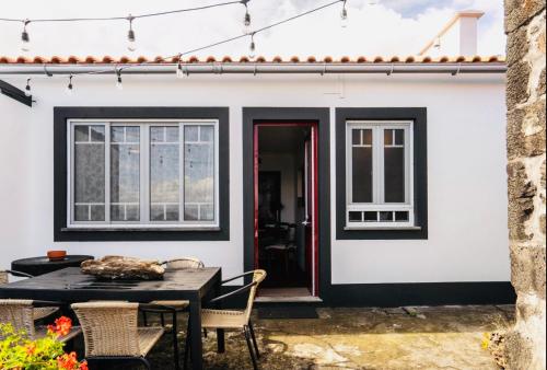 a patio with a table and chairs in front of a house at Quinta Pereirinha Farm - A Private 3 Bedroom Vacation Home, Close to Hiking w Ocean Views - Pico Island, Azores in São Roque do Pico