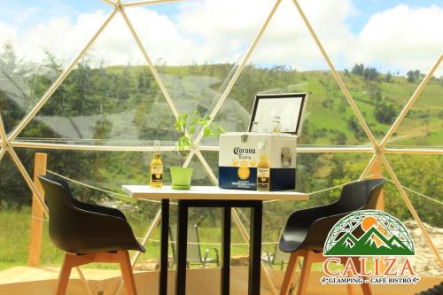 a table with a laptop on it in front of a window at Glamping Caliza La Calera in La Calera