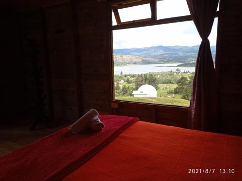 a bedroom with a large window with a red bed at Cabaña San Martin in Guatavita