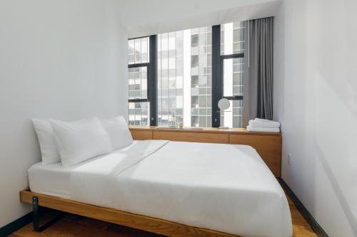 a white bed in a room with a window at Placemakr Wall Street in New York