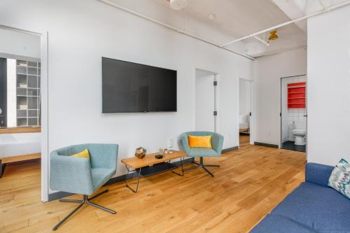a living room with two chairs and a table and a tv at Placemakr Wall Street in New York