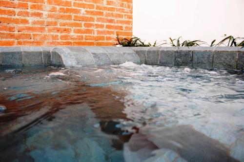una piscina de agua junto a una pared de ladrillo en Hotel Boutique Los Pasos & Spa en Antigua Guatemala
