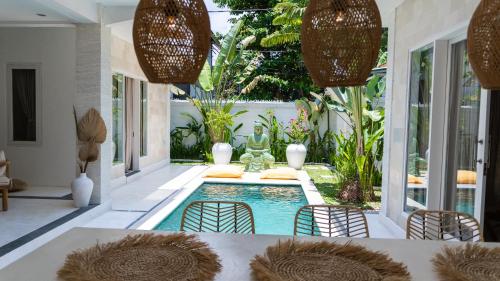 a swimming pool in the middle of a patio with chairs and a table at Villa Diola 2 in Canggu