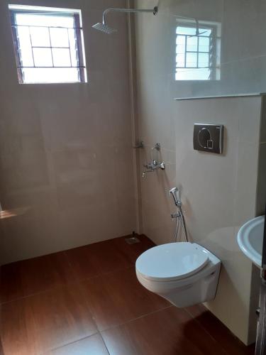 a white bathroom with a toilet and a sink at Shamrock Inn in Cochin