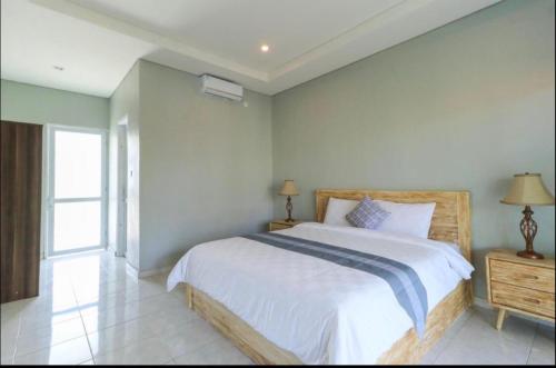 - une chambre avec un grand lit blanc et une fenêtre dans l'établissement Anyar Guesthouse Canggu, à Canggu