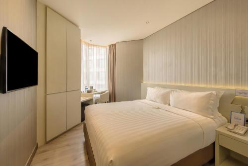 a hotel room with a bed and a television at Ashley Wahid Hasyim Jakarta in Jakarta