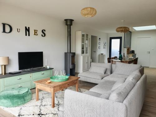 ein Wohnzimmer mit zwei Sofas und einem Fernseher in der Unterkunft Maison Les Dunes Bourgales in Gouville-sur-Mer