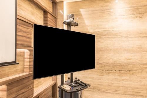 a flat screen tv on a wall with a lamp at Ashley Wahid Hasyim Jakarta in Jakarta