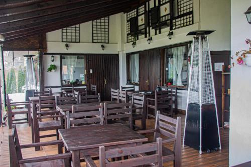 a restaurant with wooden tables and chairs and windows at Pensiunea Casa Boiereasca in Peştera