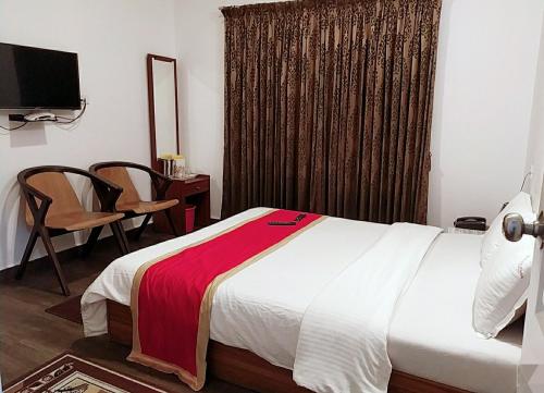 a bedroom with a bed and a chair and a television at Rosepark Residency in Ooty