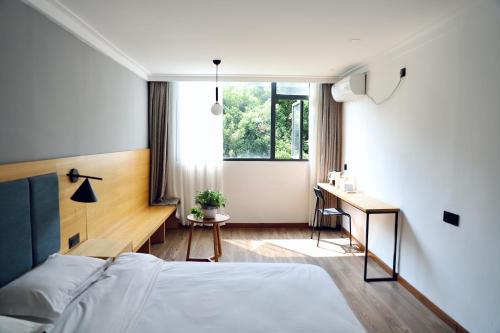 Travel light inn Guilin في قويلين: غرفة نوم بسرير ومكتب ونافذة