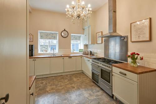 a large kitchen with white cabinets and a chandelier at Acorn Lodge Harrogate in Harrogate