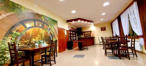 a restaurant with tables and chairs and a painting on the wall at Motel Panorama in Korczowa