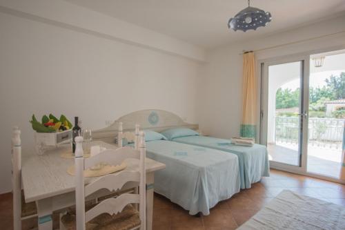 a bedroom with a bed and a table and a window at Le Residenze del Golfo di Orosei in Orosei