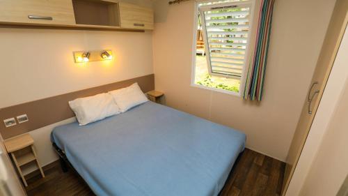 - une petite chambre avec un lit bleu et une fenêtre dans l'établissement CAMPING AZU'RIVAGE, à Azur
