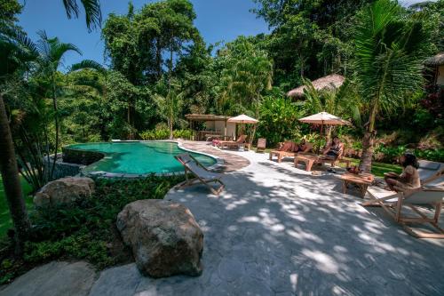 a swimming pool with people sitting in chairs next to a resort at Oasis Koh Chang in Ko Chang