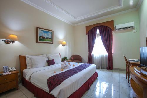 a hotel room with a bed and a television at The Royale Krakatau in Cilegon