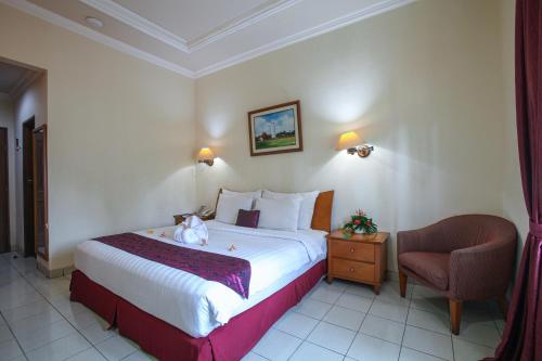 a hotel room with a bed and a chair at The Royale Krakatau in Cilegon