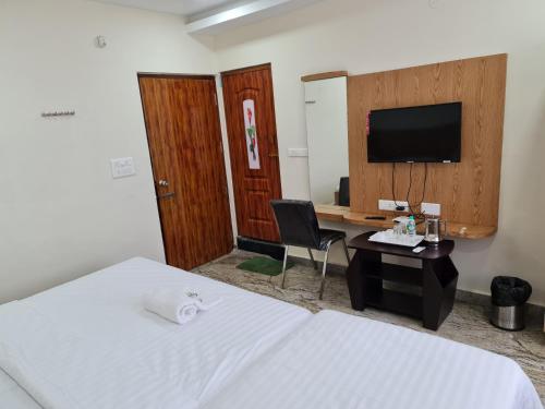 a hotel room with a bed and a desk with a television at Vijay Shree Inn in Vellore