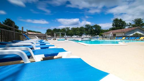 une grande piscine avec des chaises bleues et blanches dans l'établissement CAMPING AZU'RIVAGE, à Azur