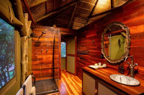 a bathroom with a sink and a mirror in a cabin at Lalibela Game Reserve Tree Tops Safari Lodge in Paterson