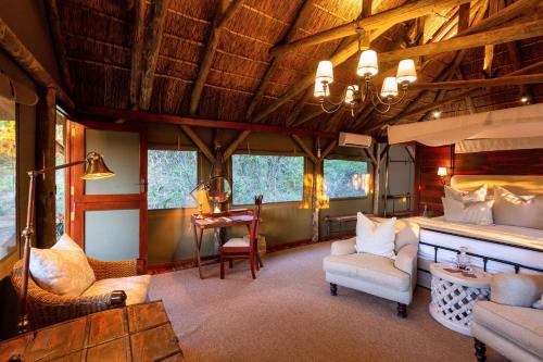 a room with a bed and chairs and a table at Lalibela Game Reserve Tree Tops Safari Lodge in Paterson