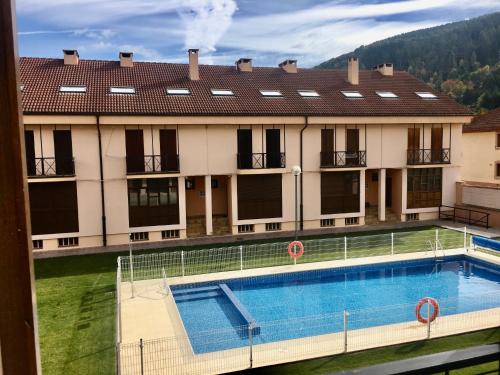 a large building with a swimming pool in front of it at Adosado Marblés con Txoko y Wifi in Ezcaray