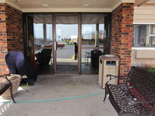 a front door of a building with a green hose at AmericInn by Wyndham West Bend in West Bend