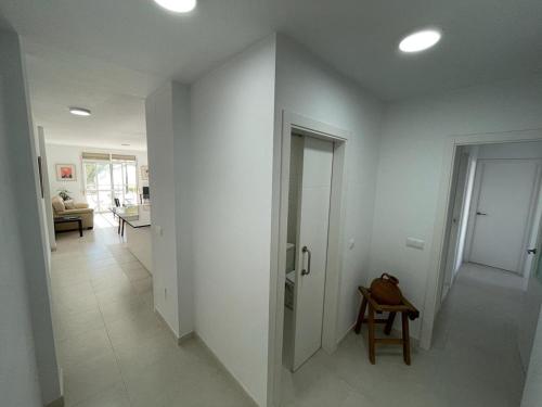 a hallway with white walls and a table and a chair at Apartamento frente a la playa Piso 3 in Estepona