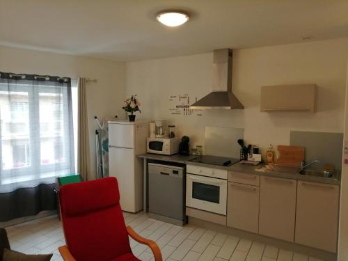 a kitchen with a white refrigerator and a red chair at Appart'Hôtel Lagnieu in Lagnieu