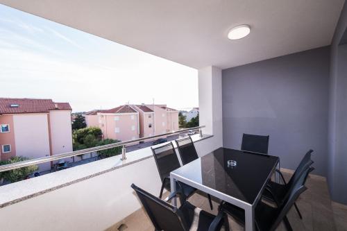een eetkamer met een tafel en stoelen op een balkon bij Apartments & Rooms Danivan Pool Villas B in Novalja