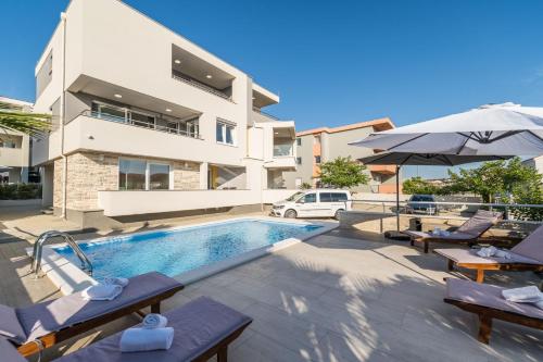 een villa met een zwembad en een gebouw bij Apartments & Rooms Danivan Pool Villas B in Novalja
