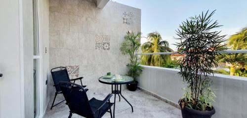 a balcony with a table and chairs and palm trees at Cozumel 568 - Vacation Rental in Cozumel