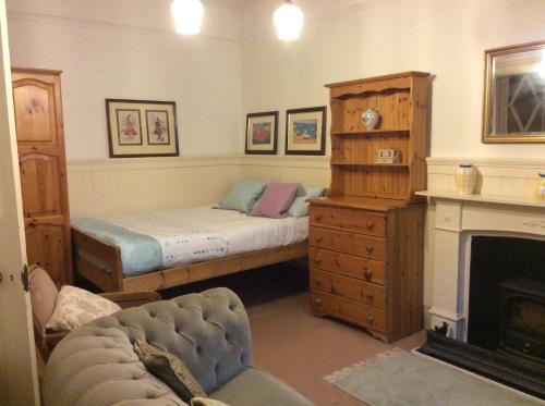 a bedroom with a bed and a dresser and a fireplace at Newhall in Glasgow