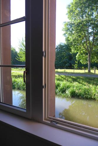 an open window with a view of a river at La Maison Carré in Wolxheim