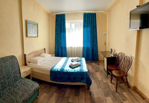 ヴォロネジにあるHotel Nordのベッド、テーブル、椅子が備わるホテルルームです。