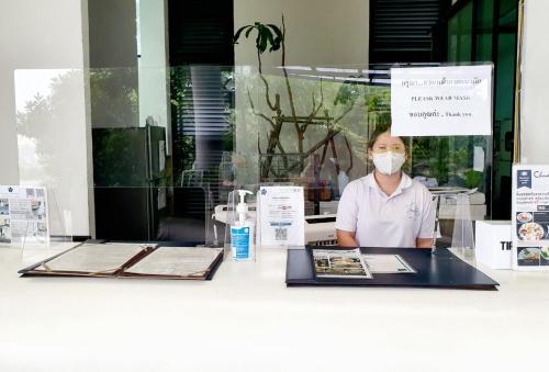 a woman wearing a mask behind a counter at Hotel Chuan Chom The High Resort Saraburi - SHA Plus in Sara Buri