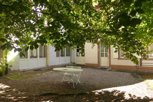 Una mesa y sillas frente a un edificio. en La Maison Carré, en Wolxheim