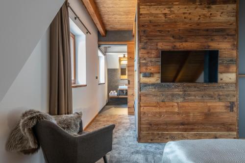 a room with a wooden wall and a chair and a television at Hotel Královka in Bedřichov