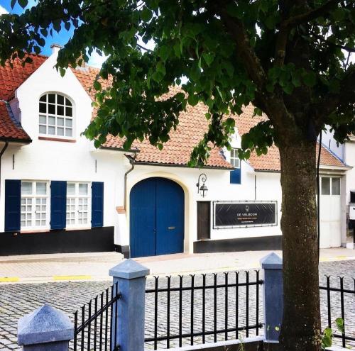 a house with a blue door and a fence at B&B De Vrijboom in Kruisem