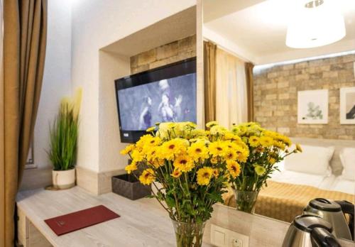 d'un salon avec des fleurs jaunes et une télévision. dans l'établissement Hotel Artist, à Tirana