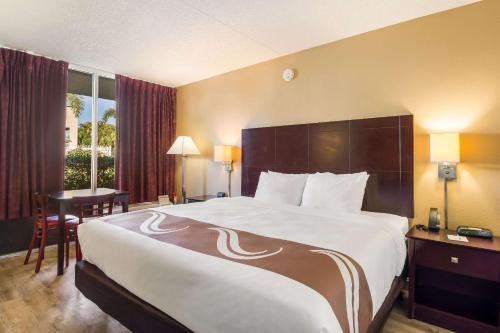 Quality Inn Bradenton - Sarasota North في برادنتون: غرفة الفندق بسرير كبير ومكتب